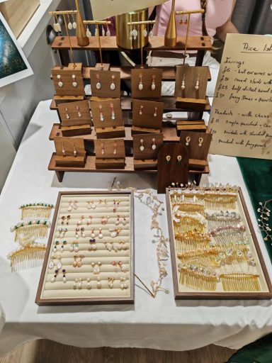 Display of various handmade jewellery, including earrings and necklaces, on a table.