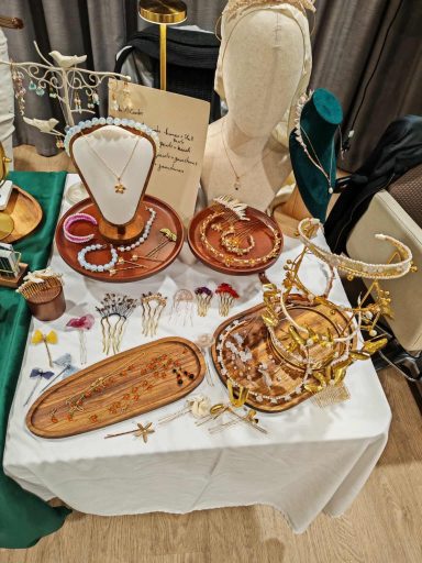 Display of various handmade jewellery items on wooden trays and stands.